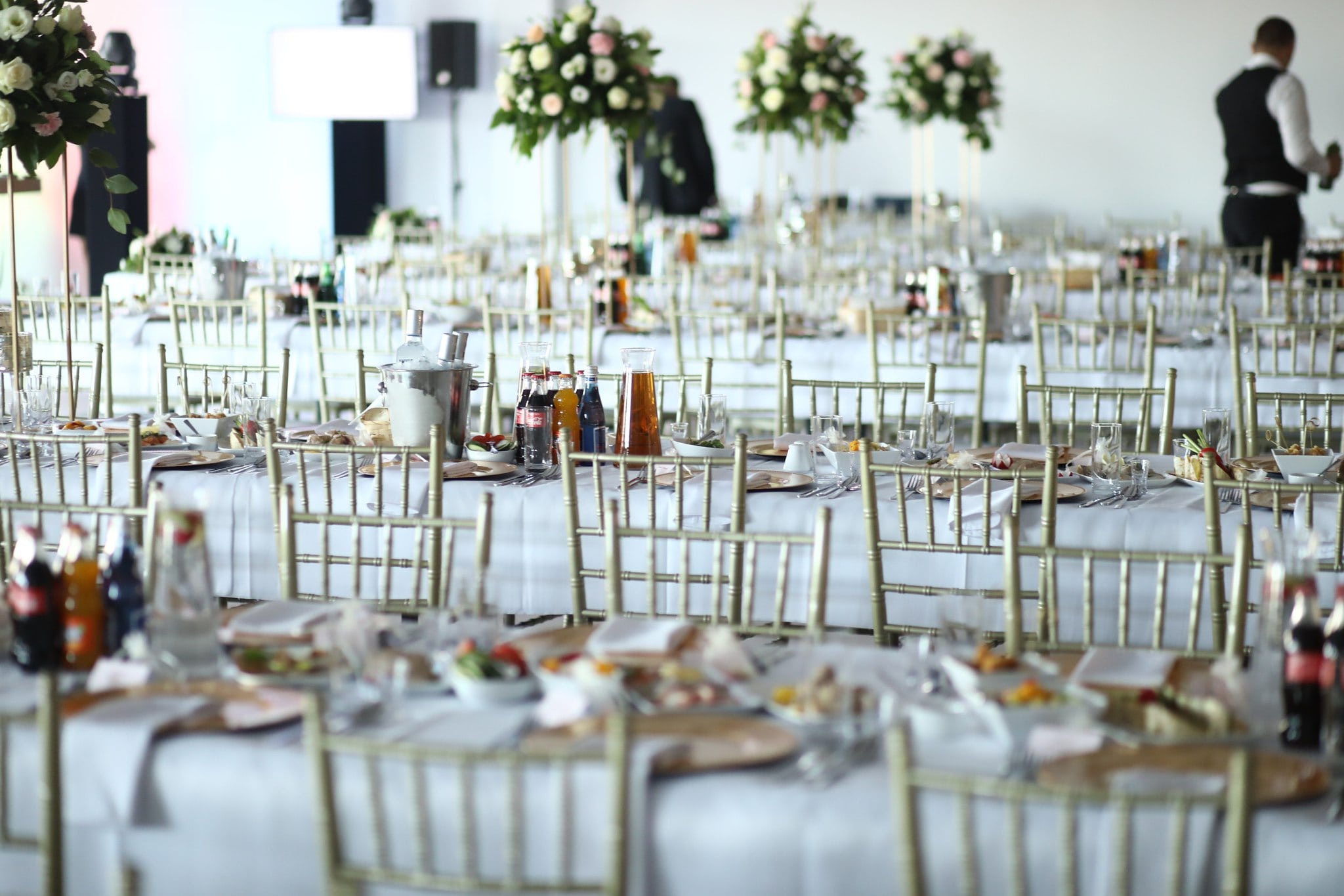 Wedding room tables decorated with plates, cutlery and flowers