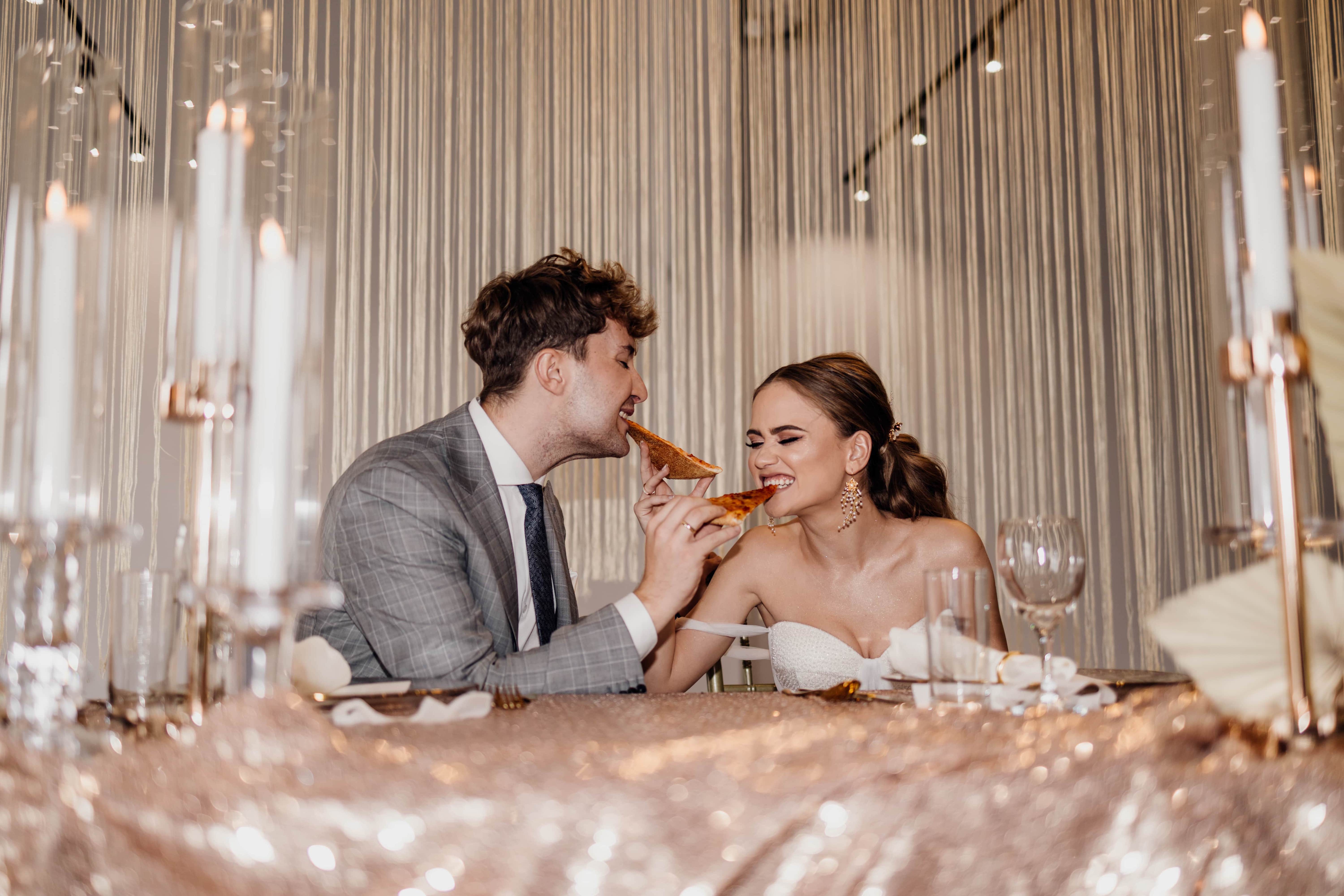 A wedding couple eating pizza